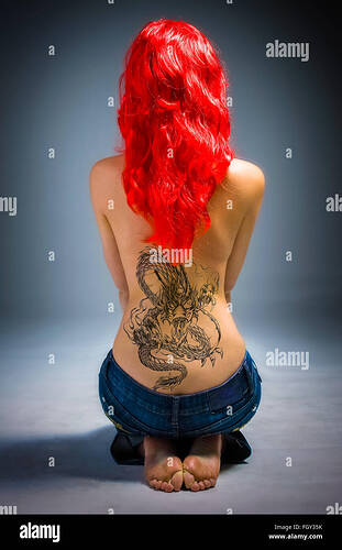 young-lady-with-a-dragon-back-tattoo-and-red-hair-seated-on-floor-FGY35K