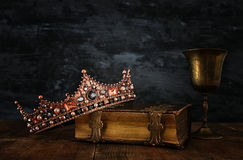 low-key-image-beautiful-queen-king-crown-old-book-next-to-ancient-cup-wine-vintage-filtered-fantasy-medieval-period-90218399